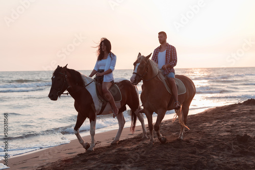 a loving couple in summer clothes riding a horse on a sandy beach at sunset. Sea and sunset in the background. Selective focus  © .shock