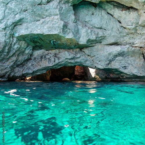 Turquoise sea water and the entrance of an underwater cave. Summer on a Greek island.