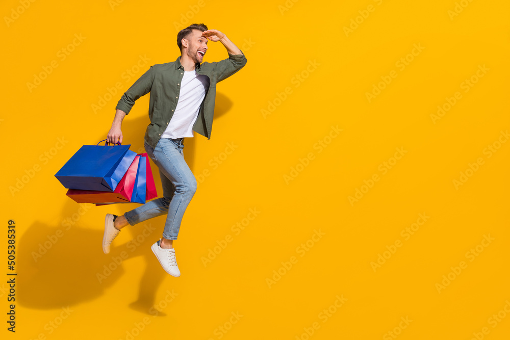 Full length body size view of attractive guy jumping carrying things running look isolated over bright yellow color background Full length body size view of attractive guy jumping carrying things running look isolated over bright yellow color background
