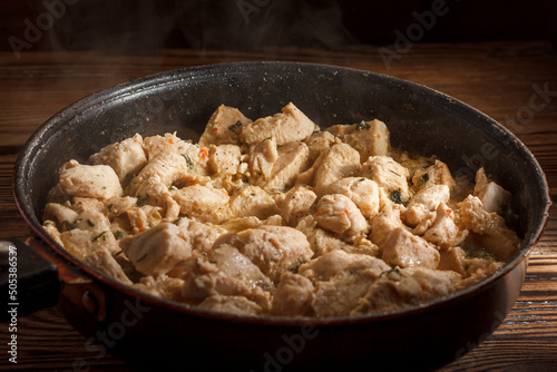 Chicken slices being friend in a pan on a wooden background