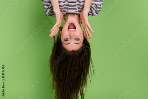 Portrait of upside down impressed cheerful lady open mouth look camera isolated on green color background