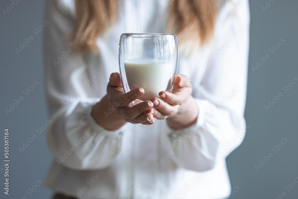 Woman hand holding glass of fresh milk on white background. Woman drinking a glass of milk in the kitchen at home. Healthy drink concept. Girl hand showing glass full of milk Woman hand holding glass of fresh milk on white background. Woman drinking a glass of milk in the kitchen at home. Healthy drink concept. Girl hand showing glass full of milk