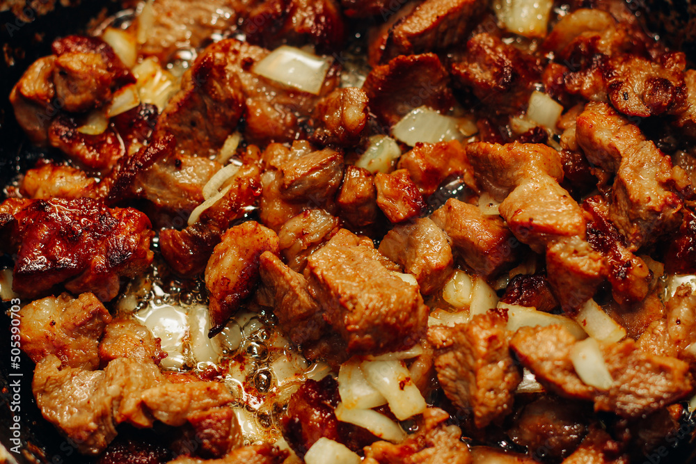 Fried pieces of meat with onions and seasonings in a frying pan close-up, meat goulash. Fried pieces of meat with onions and seasonings in a frying pan close-up, meat goulash.