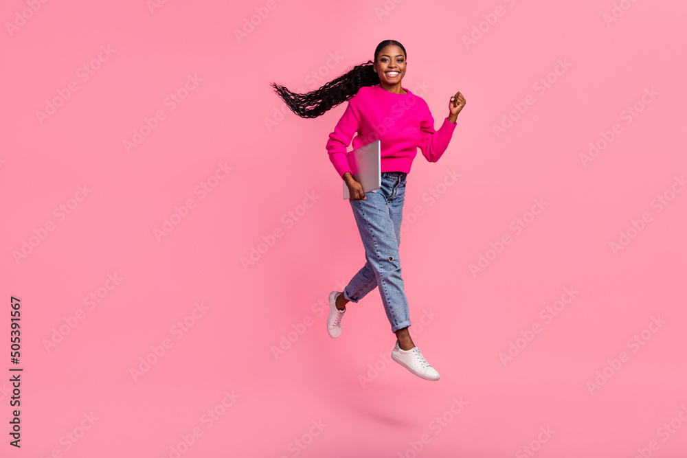 Full size photo of young brunette lady hold laptop run wear pullover jeans footwear isolated on pink background