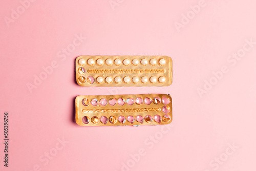 Female oral contraceptive pills empty and full blister on a pink background.