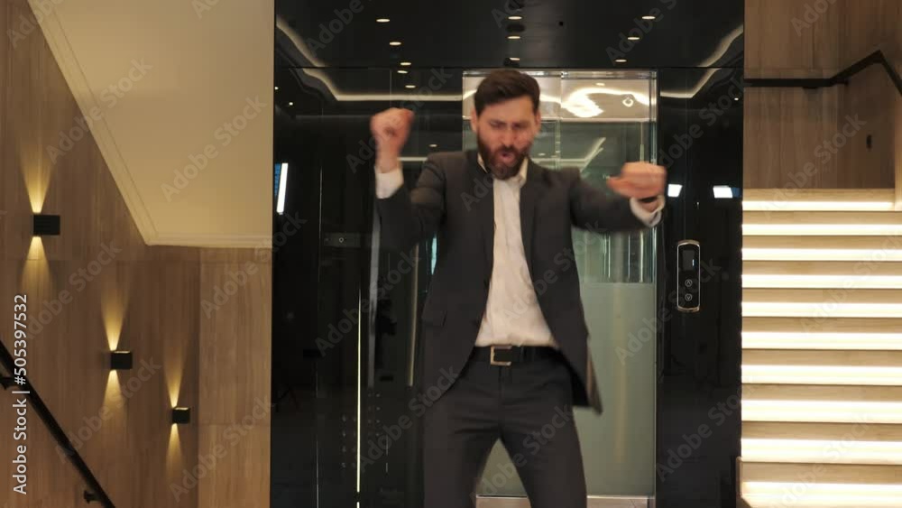 Funny excited businessman celebrating victory, dancing in modern hall office. Male person having fun enjoy job opportunities. Career people. Celebration. Man Celebrates Successful Project New Job. Funny excited businessman celebrating victory, dancing in modern hall office. Male person having fun enjoy job opportunities. Career people. Celebration. Man Celebrates Successful Project New Job.