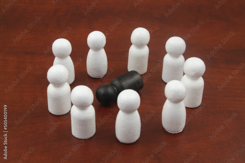 Black figure laying on wooden background in circle of white people figures. Black figure laying on wooden background in circle of white people figures.