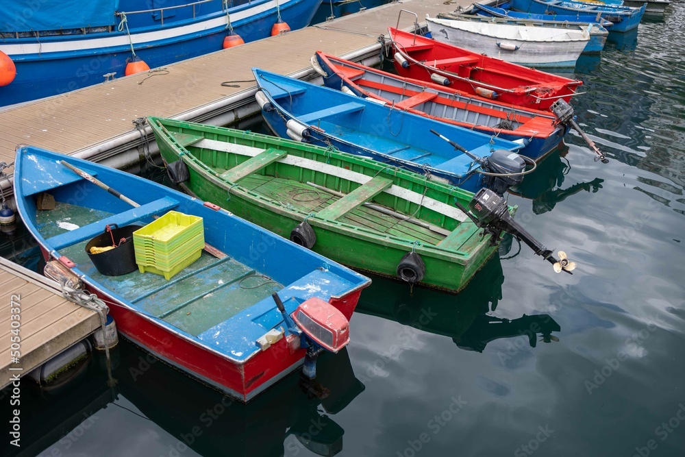 Auxiliary wooden fishing boats with outboard motor in different colors