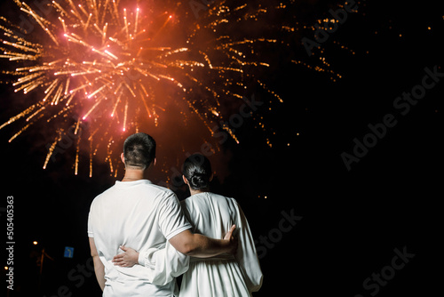 The couple embraces as they watch the beautiful fireworks in their honor. Back view