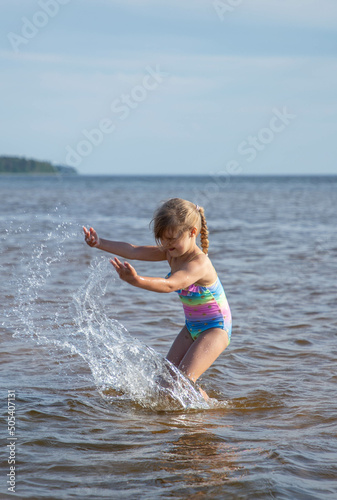 Girl of European appearance having fun in water on the beach and splashing