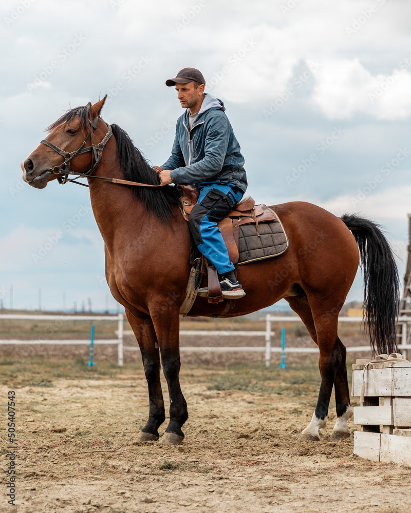Authentic portrait of horse rider. Young farmer dressed work clothes on his beautiful bay horse. Authentic portrait of horse rider. Young farmer dressed work clothes on his beautiful bay horse.