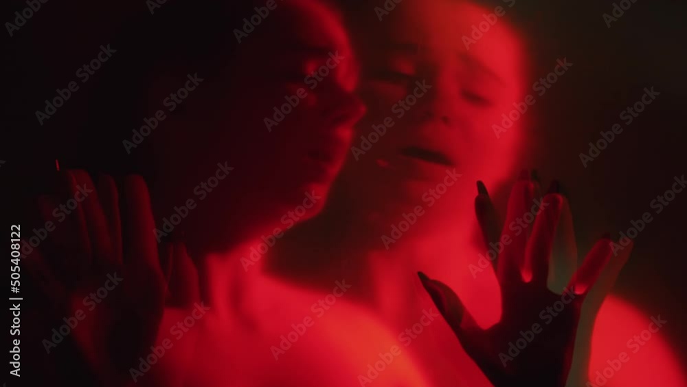 Nightmare fear. Scared woman. Haunted horror. Defocused afraid double exposure trapped female silhouette in red neon light dark out of focus background.