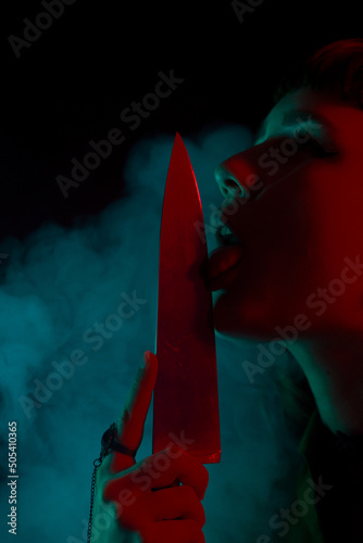 A gothic girl with a knife in smoke with dark background