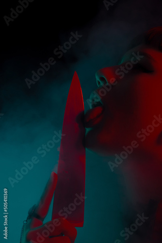A gothic girl with a knife in smoke with dark background