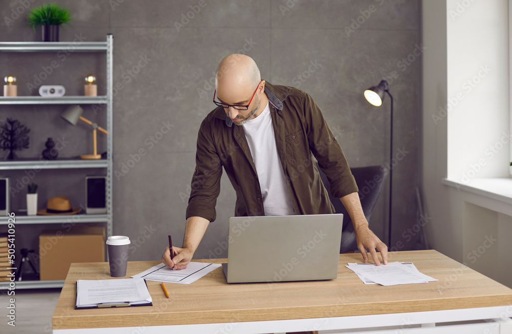 Fotografie Very busy man taking notes while working in his home office