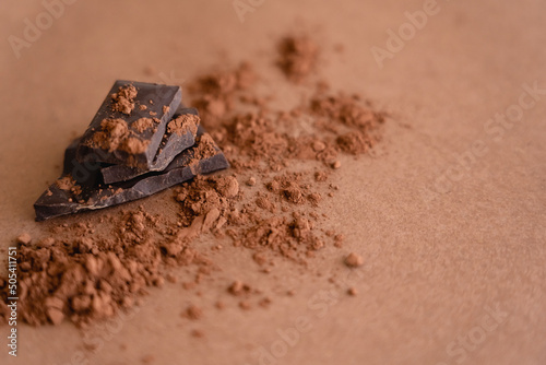 Close up view of dark chocolate and cocoa powder on brown background with copy space.