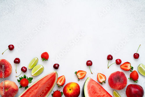 Watermelon, peach, strawberry, lime, cherry and nectarine on grey background. Slices of fresh red fruits and berries. Healthy summer diet with vitamins and antioxidants. Copy space, top view, flat lay