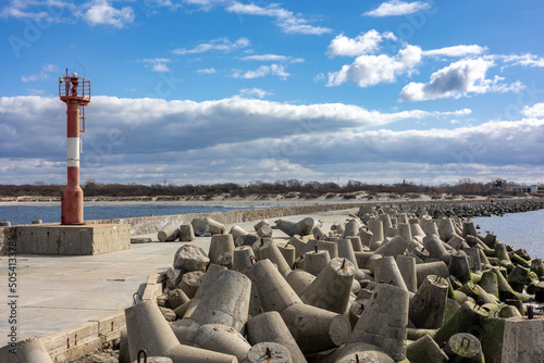 A pier with concrete breakwaters stretches from the sea to the shore. A clear sunny day with a blue sky with clouds in Baltiysk, Kalinigrad region, Russia, near the Baltic sea.