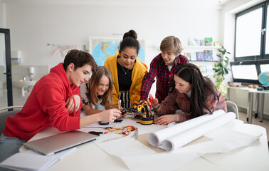 Group of students building and programming electric toys and robots at robotics classroom