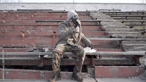 A man with gas mask eating some food on a destroyed court. Postpocalyptic embient. photo