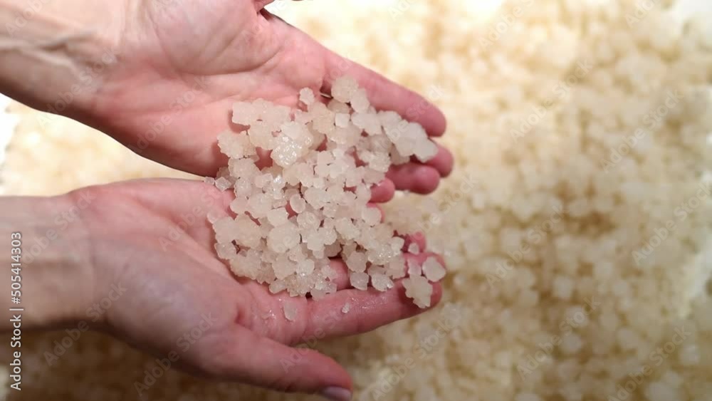 Woman's hands hold handful of medicinal salt on background of scattered salt. Salt baths used for treatment purposes in medicine and at home. Treatment salt of Dead sea Woman's hands hold handful of medicinal salt on background of scattered salt. Salt baths used for treatment purposes in medicine and at home. Treatment salt of Dead sea