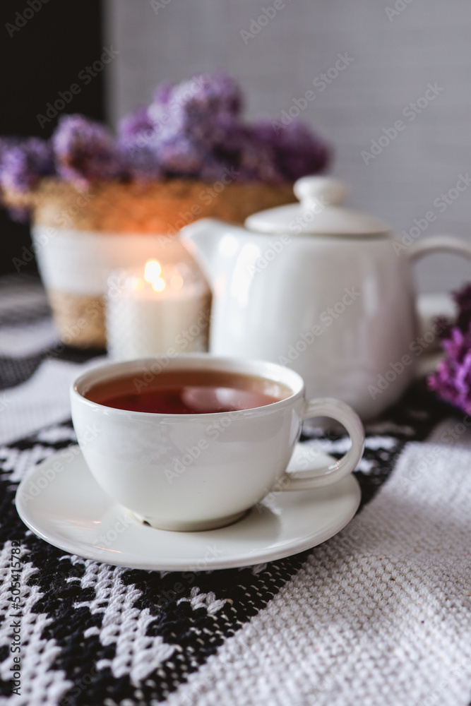A cup of tea with a teapot on a table with a lilac wicker basket, atmospheric tea party photo