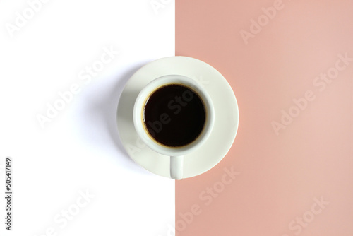 Top view of Coffee in cup with foam on a pink and white background.