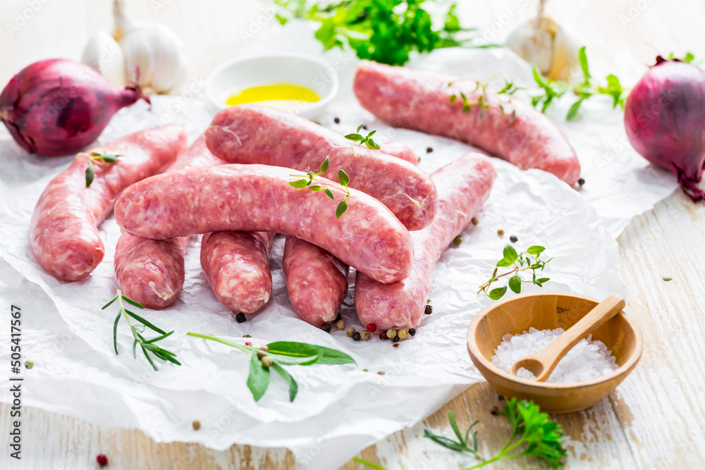 Raw sausages prepared for BBQ and grill with herbs and onions