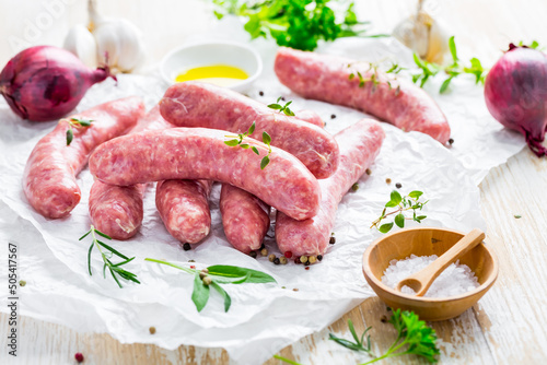 Raw sausages prepared for BBQ and grill with herbs and onions
