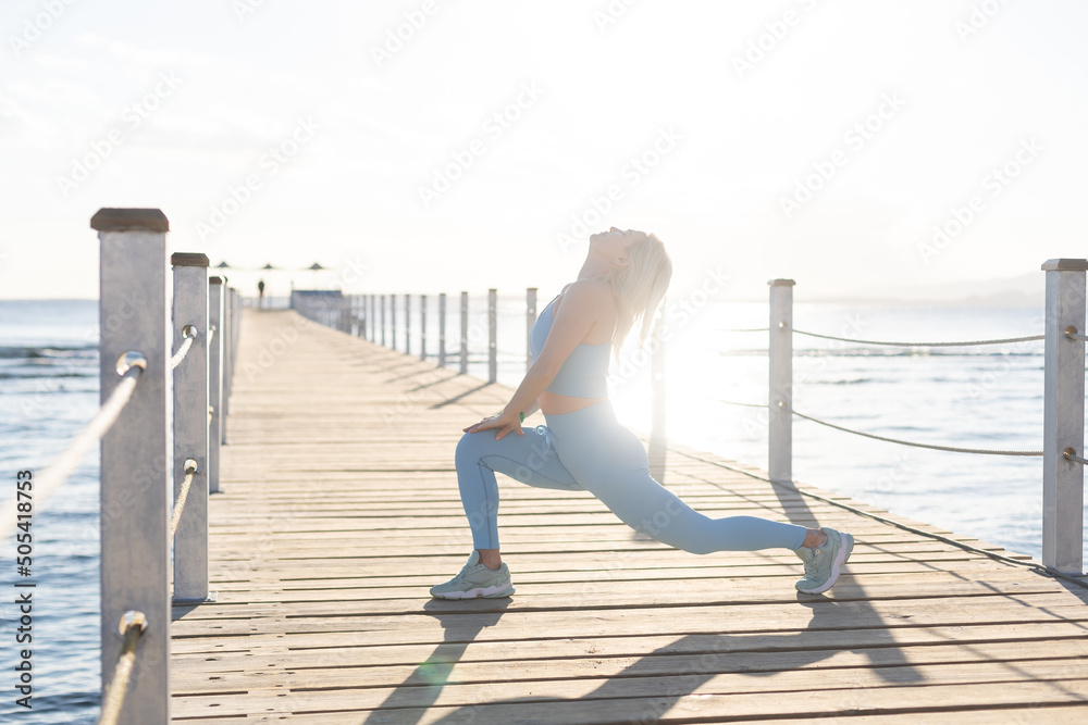 Portrait of fitness woman stretching out by the sea