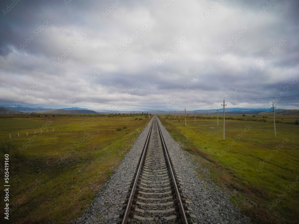 Straight single train track leading in the vast tundra of Siberia on the trans siberian railway.