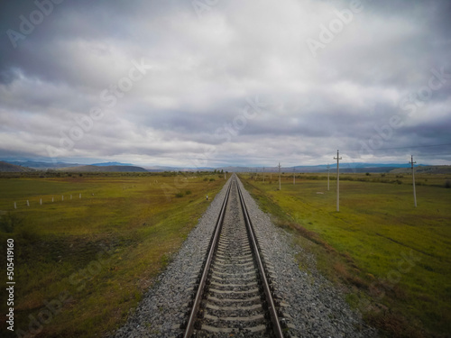 Straight single train track leading in the vast tundra of Siberia on the trans siberian railway.