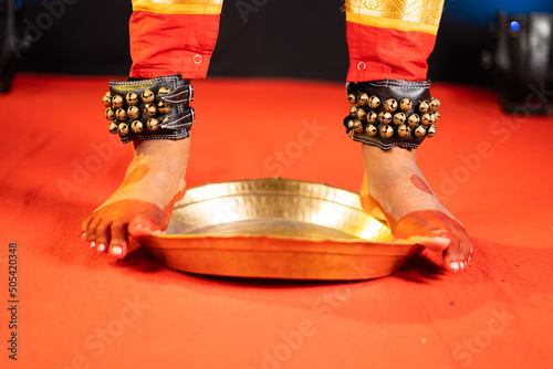 Close up shot of bharatnatyam kuchipudi artist dancing by balancing on edge of brass plate - concept of professional traditional dancer and indain culture photo