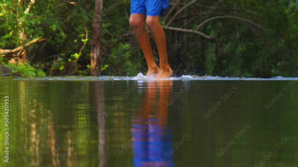 The boy dances cheerfully in the park against the backdrop of green trees. A beautiful reflection on the surface of the water of a dancing teenager. Water splash The boy dances cheerfully in the park against the backdrop of green trees. A beautiful reflection on the surface of the water of a dancing teenager. Water splash