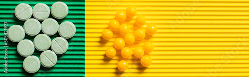 top view of round shape pills and vitamins on textured green and yellow background  banner.