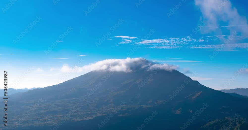 Timelapse of clouds moving near the top of a mountain. Blue sky on sunny day