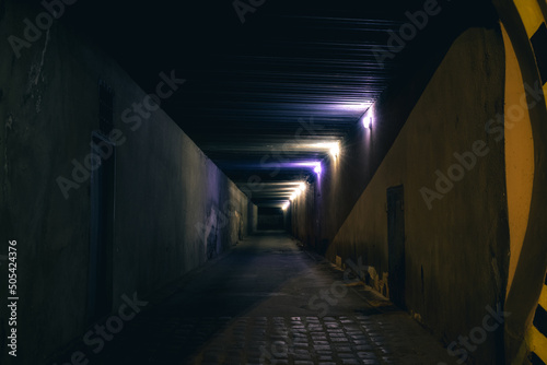 underground path road dangerous way at night with electricity lamps and wall blue and yellow colors, back street criminal district, unfocused concept of photography