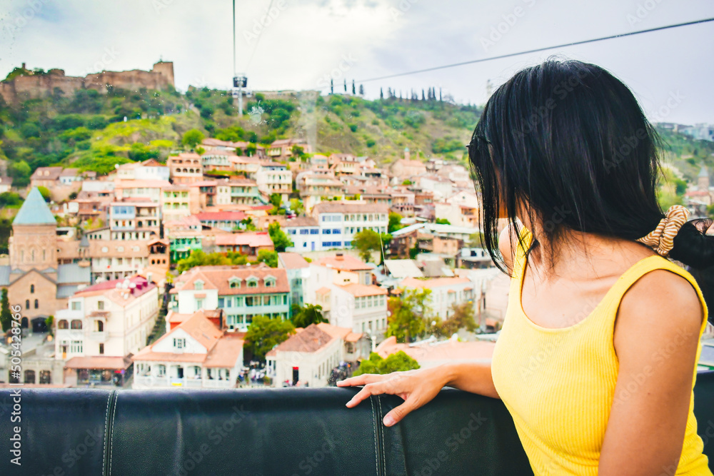 Φωτογραφία Young caucasian woman tourist look through the window to old town in cable way ,