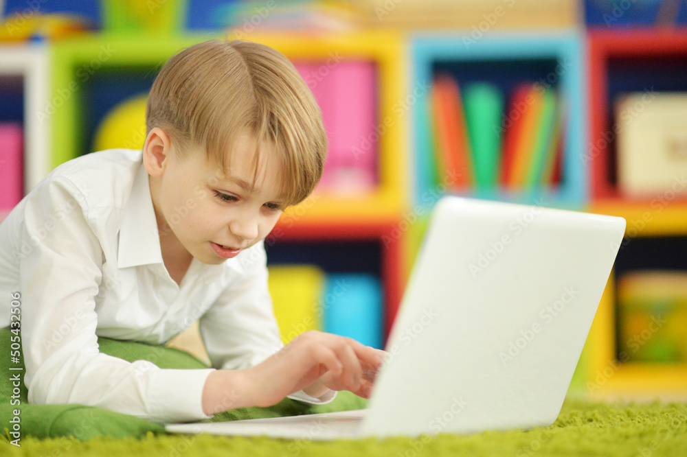 exited boy using laptop while lying on floor exited boy using laptop while lying on floor