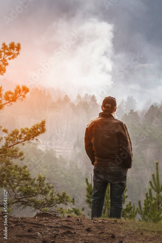a man looks at a burning fire in the forest. tourist or forest arsonist