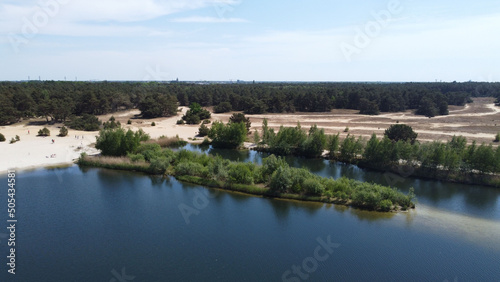 Aerial view of lake surrounded by growing bushes and sandy beach in Belgium photo