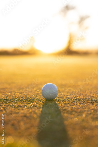 Close-up of golf ball on grassy landscape against clear sky during sunset, copy space