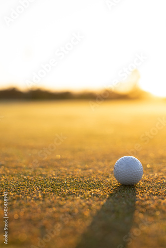 View of golf ball on grassy landscape against clear sky during sunset, copy space
