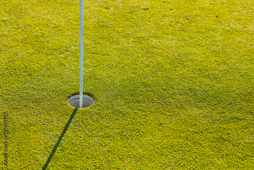 High angle view of flagstick in hole amidst grassy land at golf course during sunny day