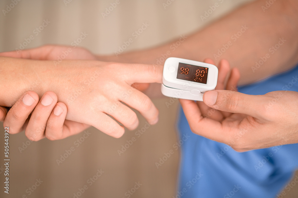 Experienced doctor measuring the oxygen saturation in the blood - obrazy, fototapety, plakaty 