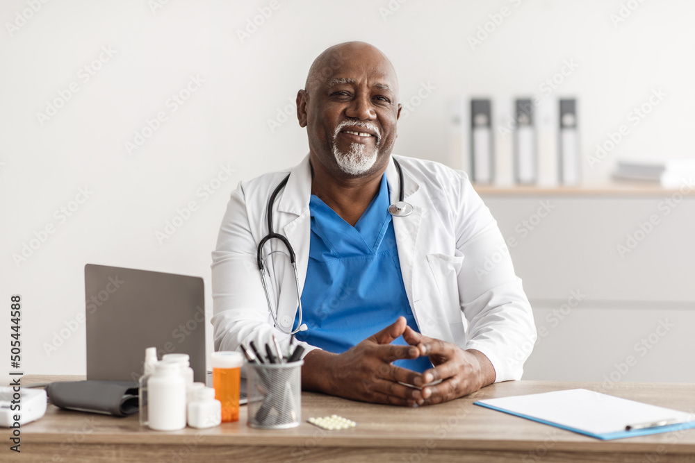 Portrait of smiling doctor looking at camera sitting at desk Portrait of smiling doctor looking at camera sitting at desk