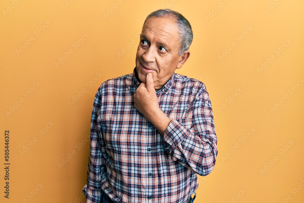 Handsome senior man with grey hair wearing casual shirt with hand on chin thinking about question, pensive expression. smiling with thoughtful face. doubt concept. Handsome senior man with grey hair wearing casual shirt with hand on chin thinking about question, pensive expression. smiling with thoughtful face. doubt concept.