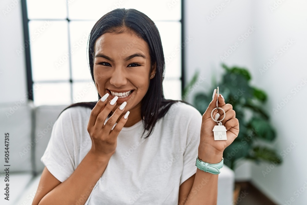 Young hispanic woman holding keys of new home laughing and embarrassed ...