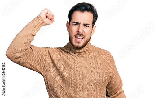 Young hispanic man wearing casual clothes angry and mad raising fist frustrated and furious while shouting with anger. rage and aggressive concept. © Krakenimages.com