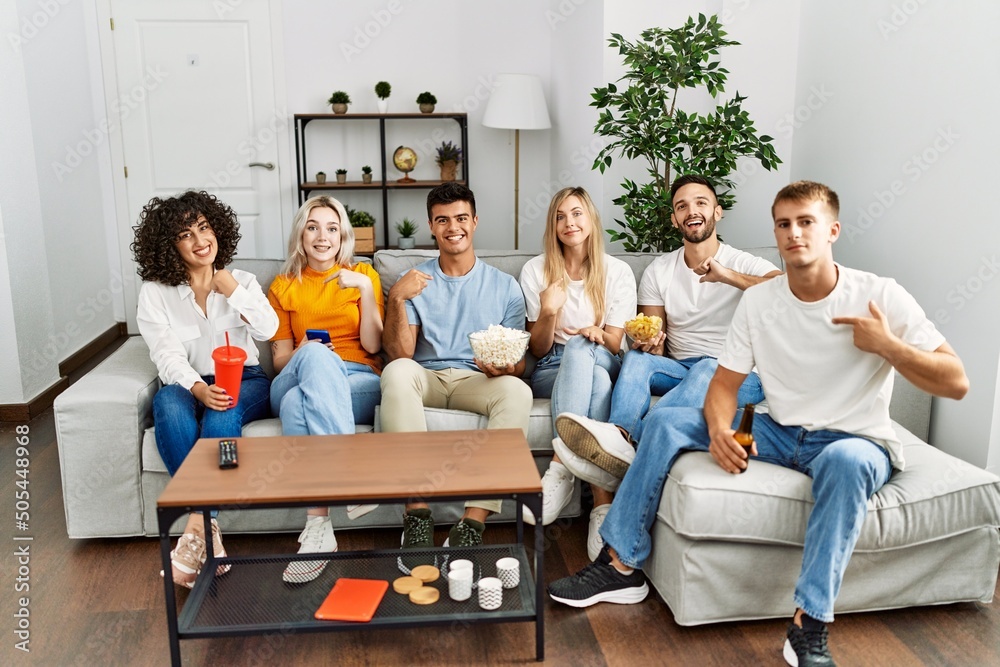 Group of people eating snack sitting on the sofa at home pointing finger to one self smiling happy and proud Group of people eating snack sitting on the sofa at home pointing finger to one self smiling happy and proud